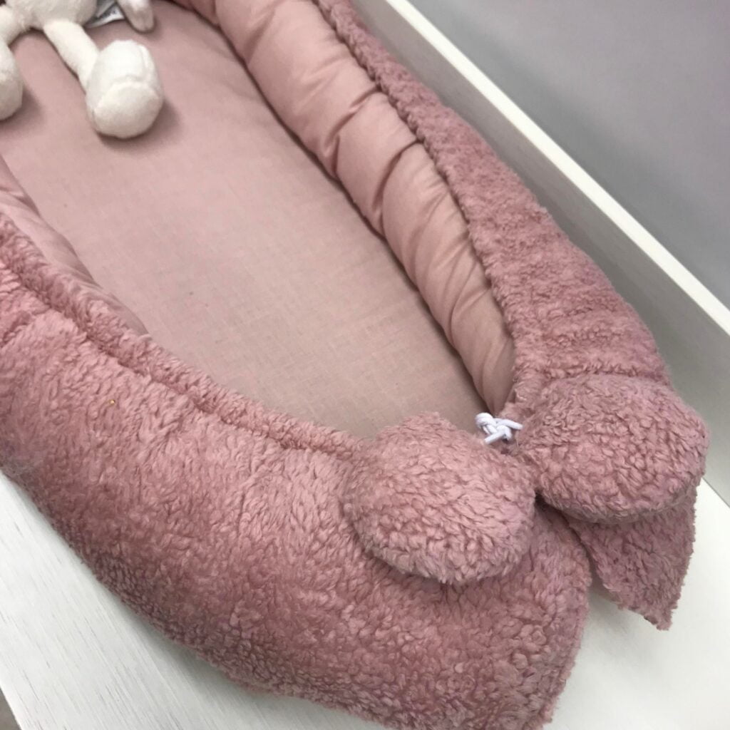 BEREZACHT is dit schattige nestje van teddiestof. De binnenkant is van puur katoen en aan het koord hangen leuke teddybolletjes Wat zal je kleine hier heerlijk in slapen.